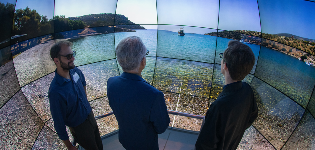 Three people in front of immersive image of ocean